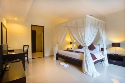 a bedroom with a canopy bed and a desk at Ageratum 4 BR Villa Private Pool in Seminyak