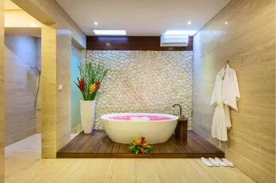 a bathroom with a bath tub and a vase of flowers at Luxury 3 BR Private Pool Villa in Seminyak