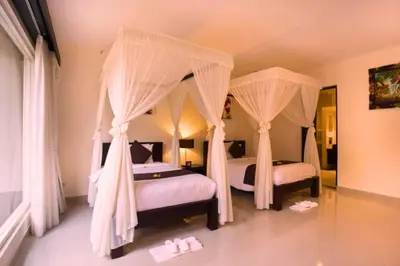 a bedroom with two beds with mosquito nets and slippers at Dahlia Mentari 2 BR Private Pool Villa in Seminyak