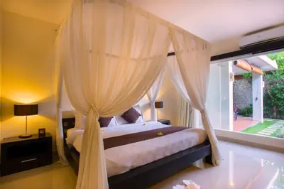 a bedroom with a canopy bed with a window at Dahlia Mentari 2 BR Private Pool Villa in Seminyak
