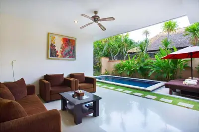 a living room with a couch and a table and a pool at Allamanda 3 BR Private Pool Villa in Seminyak