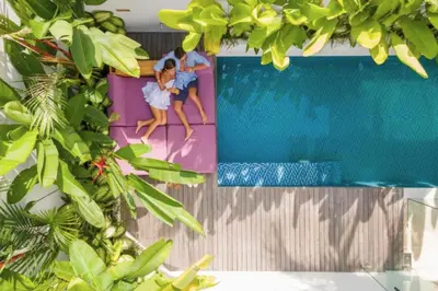 a picture of two girls sitting on the edge of a swimming pool at Modern 3 BR Private Pool Villa in Legian