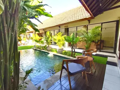 a pool with two chairs and a table next to a house at Villa JES - 4 Bedroom Villa - Legian in Legian