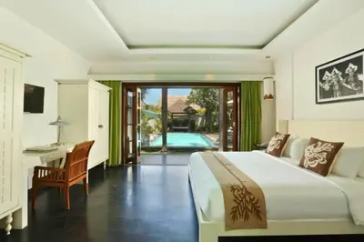 a bedroom with a bed and a desk and a pool at Cozy 2 BR Private Pool Villa in Seminyak