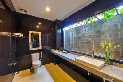 a bathroom with a toilet and a sink and a window at Entire 3 BR Private Pool Villa in Seminyak