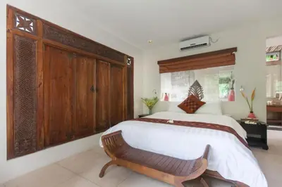 a bedroom with a large bed and a wooden cabinet at Clover 3 BR Private Pool Villa in Canggu