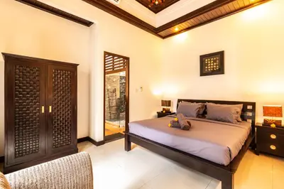 a bedroom with a bed and a chair in it at PROMO Uniquely Styled Spacious 3bd Villa in Kerobokan