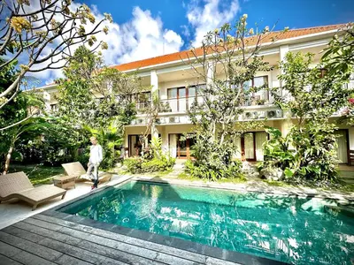 a person standing next to a swimming pool in front of a building at Bali Telaga Hati Yoga Healing and Retreat Center Villa in Sanur