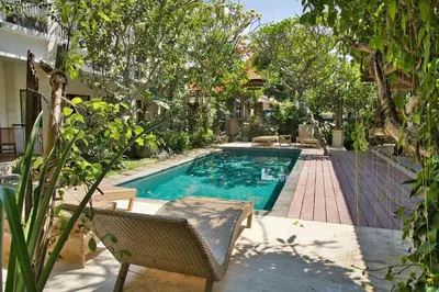 a swimming pool in a yard with a chair and trees at Bali Telaga Hati Yoga Healing and Retreat Center Villa in Sanur