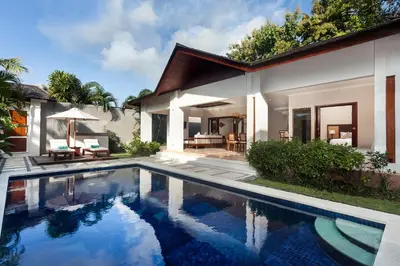 a villa with a swimming pool in front of a house at Ghana Villa Seminyak by GenuineHost in Seminyak