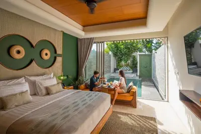 a man and woman sitting on a couch in a bedroom at Romantic 1BR Private Pool Villa in Kerobokan