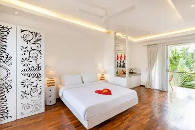 a white bedroom with a large white bed with flowers on it at Cosy 1 Bd Pvt Apartment with shared kitchen and pool in Seminyak