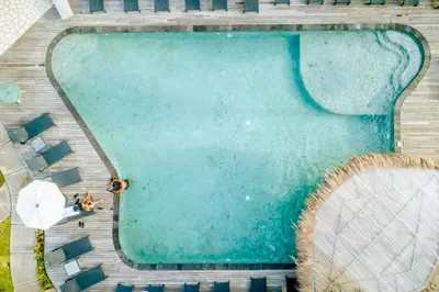 an overhead view of a swimming pool with two people and an umbrella at One BR Bungalow Cozy Place in Canggu