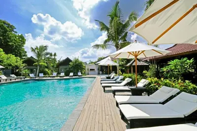 a pool at a resort with lounge chairs and an umbrella at One BR Bungalow Cozy Place in Canggu