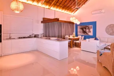a kitchen with white cabinets and a living room at Kamila Aranne 3 BR Private Pool Villa in Jimbaran