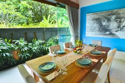 a dining room with a wooden table and a large window at Kamila Aranne 3 BR Private Pool Villa in Jimbaran