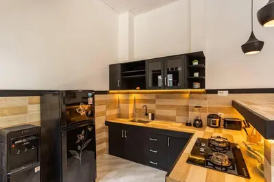 a kitchen with black cabinets and a black refrigerator at Comfy 3bd Family Villa with Private Pool in Central Location in Kerobokan
