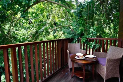 a wooden deck with two chairs and a table on it at Ari Ayra 1 BR Private Pool Villa in Jimbaran