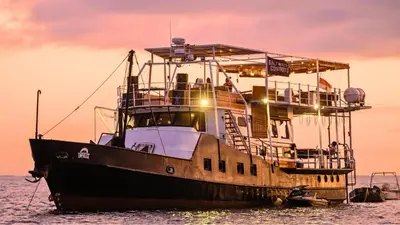 a boat sitting in the water at sunset at Floating Hotel SALTWATER COWBOYS in Kuta