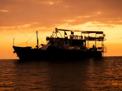 a boat sitting in the water at sunset at Floating Hotel SALTWATER COWBOYS in Kuta