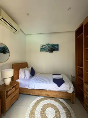 a bedroom with a bed and a lamp and a table at The Golden Serendipity Villa Seminyak in Seminyak