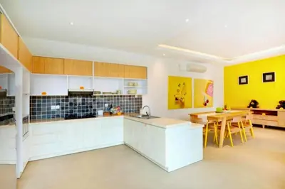 a kitchen with white cabinets and a yellow wall at Sweet 3 BR Private Pool Villa Garden View in Kerobokan