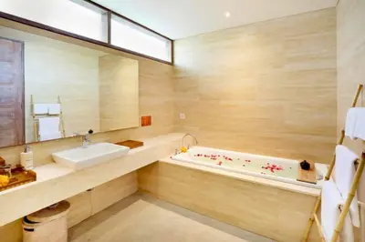 a bathroom with a tub and a sink and a mirror at Sweet 3 BR Private Pool Villa Garden View in Kerobokan