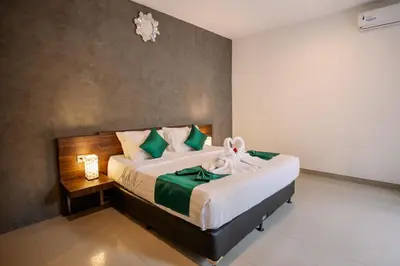 a bedroom with a large bed with green and white pillows at Taman Bali Villa Kerobokan in Kerobokan