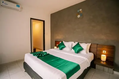 a bedroom with a large bed with green and white pillows at Taman Bali Villa Kerobokan in Kerobokan