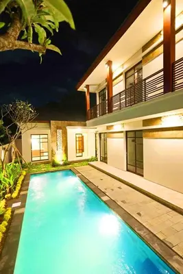 a swimming pool in front of a house at night at Dirga's House Sanur View by EPS in Sanur