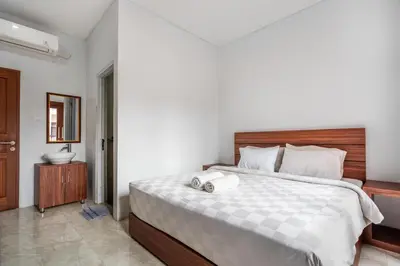 a bedroom with a large bed with a wooden headboard at Dukuh Segara Guest House in Legian