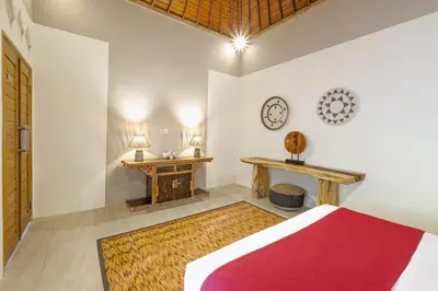 a bedroom with a bed and two tables and a clock at VILLA LA FELICITA in Seminyak