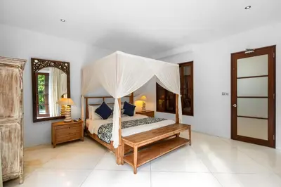 a bedroom with a canopy bed and a mirror at Sahaja Villa by Betterplace in Canggu