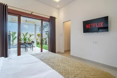 a bedroom with a bed and a tv on a wall at Aleksa - Villa with Rooftop&Rice Field View in Canggu