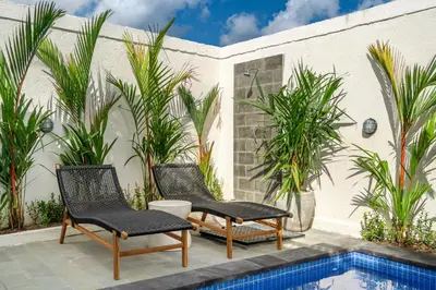 a patio with two chairs and a swimming pool at Aleksa - Villa with Rooftop&Rice Field View in Canggu