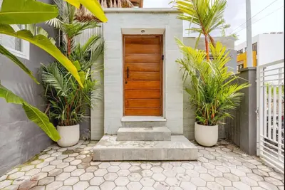 a wooden door in a house with two potted plants at Villa Karibu Canggu-2BR with pool & rooftop in Canggu