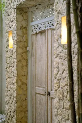 a wooden door on a stone building with two lights at Villa Chloe by Pertama Management in Seminyak