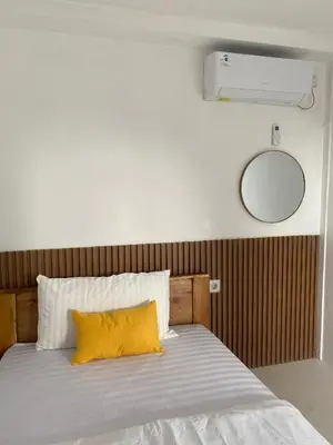 a bedroom with a bed with a yellow pillow at WIJA's Bali Homestay in Legian