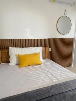 a large white bed with a yellow pillow on it at WIJA's Bali Homestay in Legian