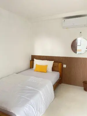 a bedroom with a bed with a yellow pillow on it at WIJA's Bali Homestay in Legian