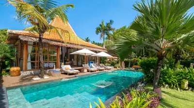a swimming pool in front of a house with palm trees at Desa Roro Estate by Villa Finder in Canggu