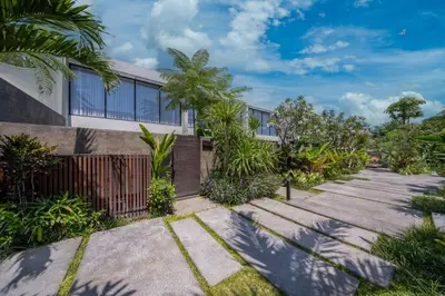 a building with a pathway and trees in front of it at Umalas Creek Villas in Canggu