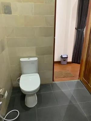 a bathroom with a white toilet in a room at Wikans Villa in Kuta