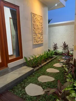 a garden in front of a house with stepping stones at Wikans Villa in Kuta