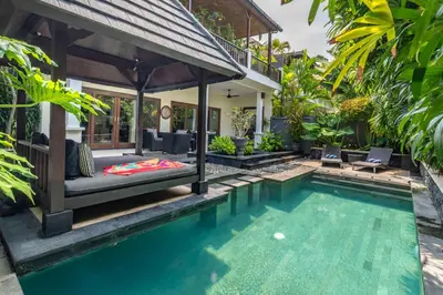 a villa with a swimming pool and a house at Villa Teratai in Seminyak