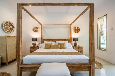 a bedroom with a large bed with a wooden frame at Kupu-Kupu Villa by iBali Management in Canggu