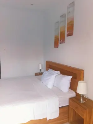 a bedroom with two beds with white sheets and two lamps at WJ Guest house in Kerobokan