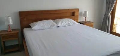 a bed with two white pillows and two lamps at WJ Guest house in Kerobokan