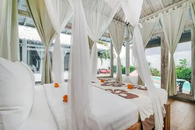 a bedroom with two beds with white drapes at Villa Laksmana 1 in Canggu