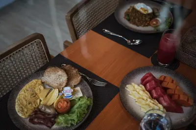 a table with two plates of breakfast food on it at Casa De Gracia Sanur Beach by Nagisa Bali in Sanur